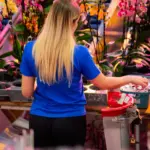 Pracownica przy pracy w szklarni z kwiatami.
